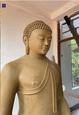 Large reclining Buddha sculpture finished in stone texture inside a forest clearing