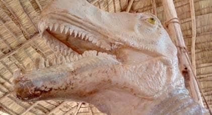 Life-size concrete dinosaur sculpture set into prehistoric style foliage