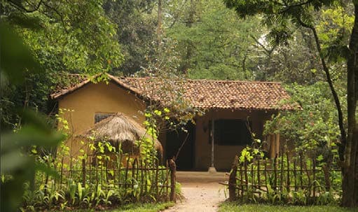 Recreated village dwelling showing traditional thatched roof and clay utility pots in the yard